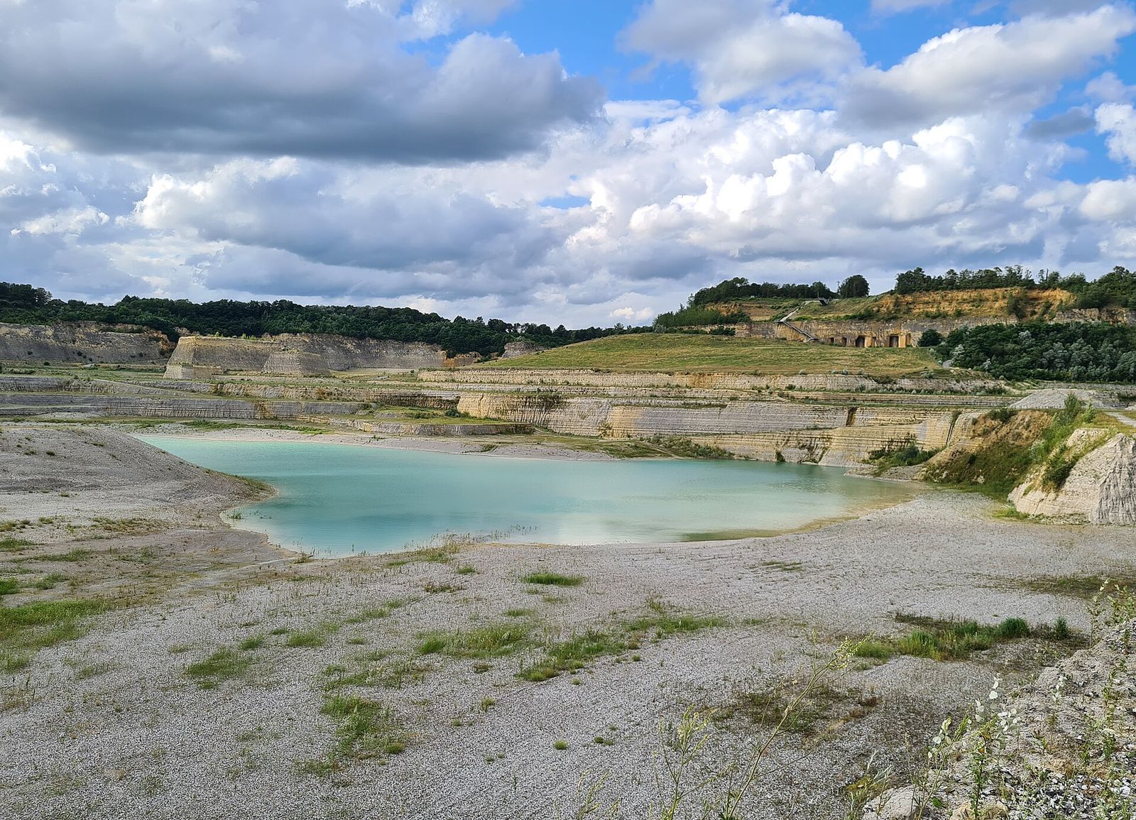 Turquoise plas op de bodem van de ENCI-groeve, omringd door getrapte kalksteenwanden